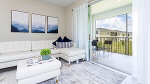 A modern living room with a white sectional sofa, a coffee table with a plant, and three framed pictures on the wall.