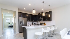 A modern kitchen with dark cabinets, a white island, and bar stools.
