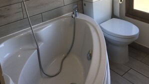 Une salle de bain avec une baignoire, des toilettes et une fenêtre.