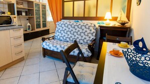 A compact kitchen with a microwave, cabinets, and a dining area with a chair and table. - Cosmopoli - Sogni di Mare (Portoferraio)