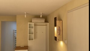 A hallway with a white door, a small shelf with a towel, and a sign on the wall. - The Finca - Your vacation in the Spanish Rhön (Hünfeld)