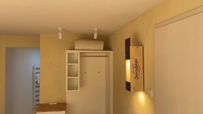 A hallway with a white door, a small shelf with a towel, and a sign on the wall. - The Finca - Your vacation in the Spanish Rhön (Hünfeld)