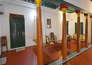 A room with a swing, wooden chairs, and a green door. - Villa Sentosa (Puducherry)