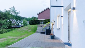 A modern house with a paved driveway, a potted plant, and a solar panel on the roof.