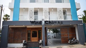 Um hotel chamado Wind Chimes, com fachada moderna, portas de madeira e uma motocicleta estacionada na frente.