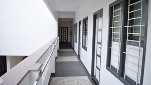 Um corredor com ladrilhos estampados, corrimão e janelas com grades metálicas.
