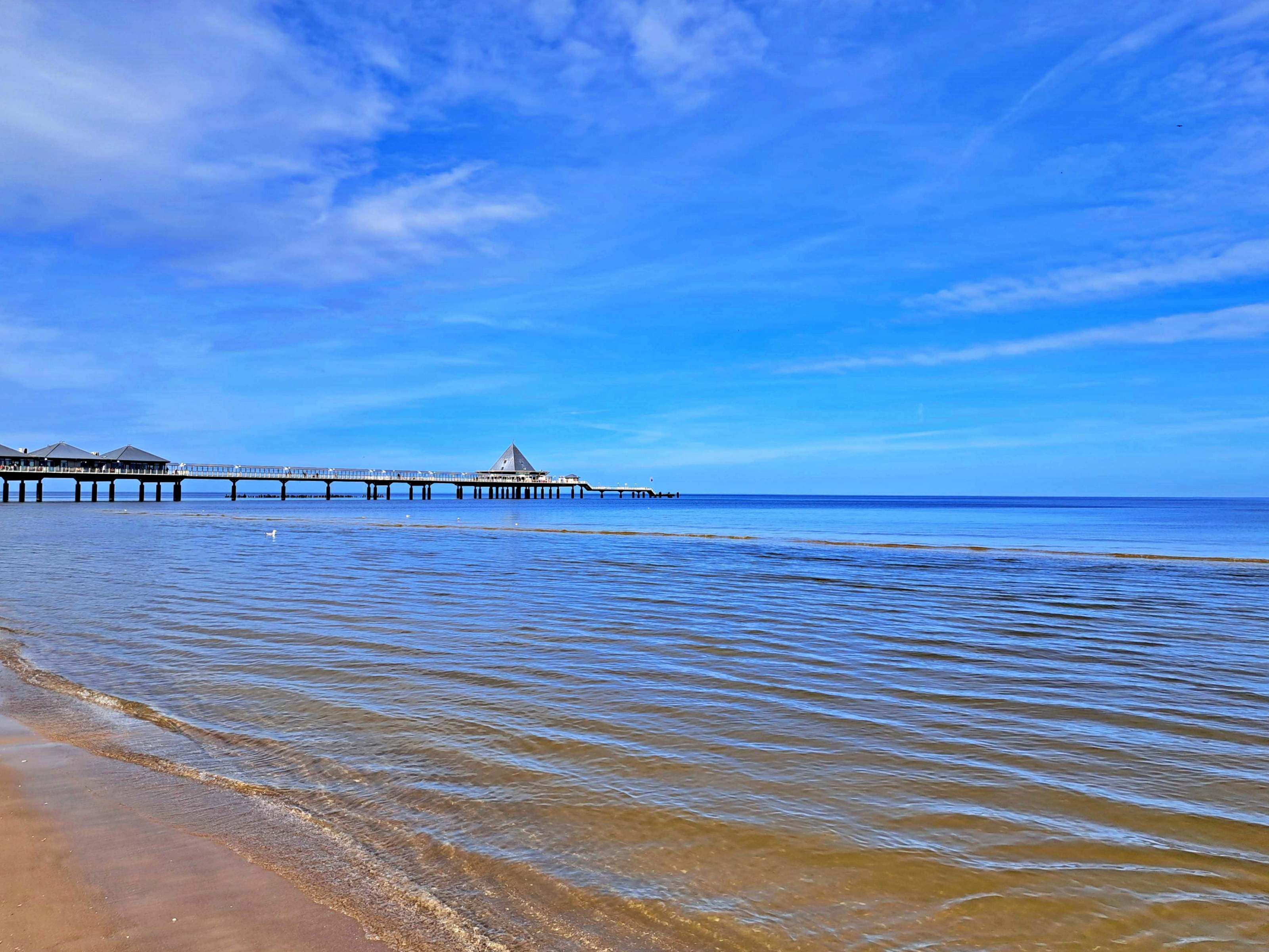 A pier extending into calm waters with clear skies.