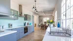 A spacious kitchen with light blue cabinets, a central island, and a large window providing natural light. - Quiet 50's cottage - 12 p. - Private park & pool (Fourcès)