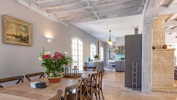 A dining area with a wooden table and chairs, a vase of flowers, and a painting on the wall. - Quiet 50's cottage - 12 p. - Private park & pool (Fourcès)