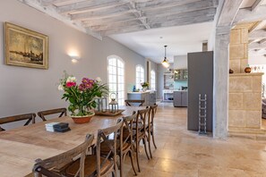 A dining area with a wooden table and chairs, a vase of flowers, and a painting on the wall. - Quiet 50's cottage - 12 p. - Private park & pool (Fourcès)