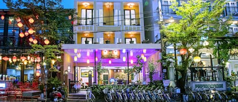 A building with multiple balconies, a row of bicycles parked in front, and a sign indicating a restaurant or cafe.