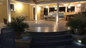 Un patio al aire libre con mesa y sillas, rodeado de plantas en macetas.