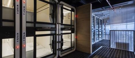 A modern hotel room with a large window, a bed, and a small seating area.