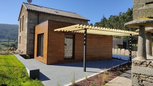 A modern house with a stone tower, wooden exterior, and a pergola. - A Casa de Costa (Laxe)
