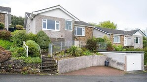 A two-story house with a stone facade, a front garden with a small staircase, and a garage. - Peaceful Home in Looe with Stunning Views (Looe)