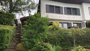 A two-story house with a stone staircase leading to the entrance, surrounded by lush greenery and a well-maintained garden. - Gîte LE Petit Renard (Dabo)