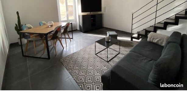 Uma sala de estar moderna com um sofá, uma mesa de jantar com cadeiras, uma escada e uma televisão.