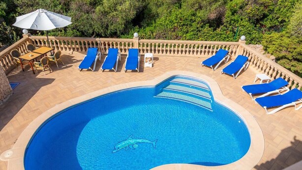 Piscina amb gandules blaves i una taula amb cadires.