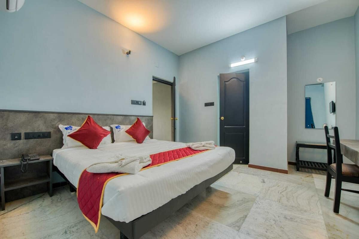A hotel room with a bed, bedside table, and a desk with a chair.