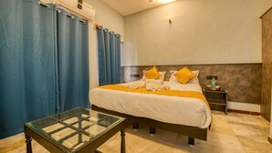 A hotel room with a bed, a glass table, a nightstand, and a ceiling fan. - Corbelli Residency  (Puducherry)