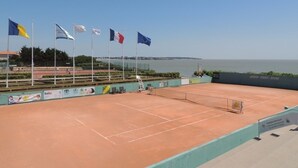 A tennis court with multiple flags, a clear sky, and a view of the sea. - 2-Bedroom Apartment in City Center with Terrace and Private Parking in Royan (Royan)