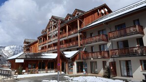 A multi-story wooden building with balconies, a ski lift, and a sign for 'neemys'.