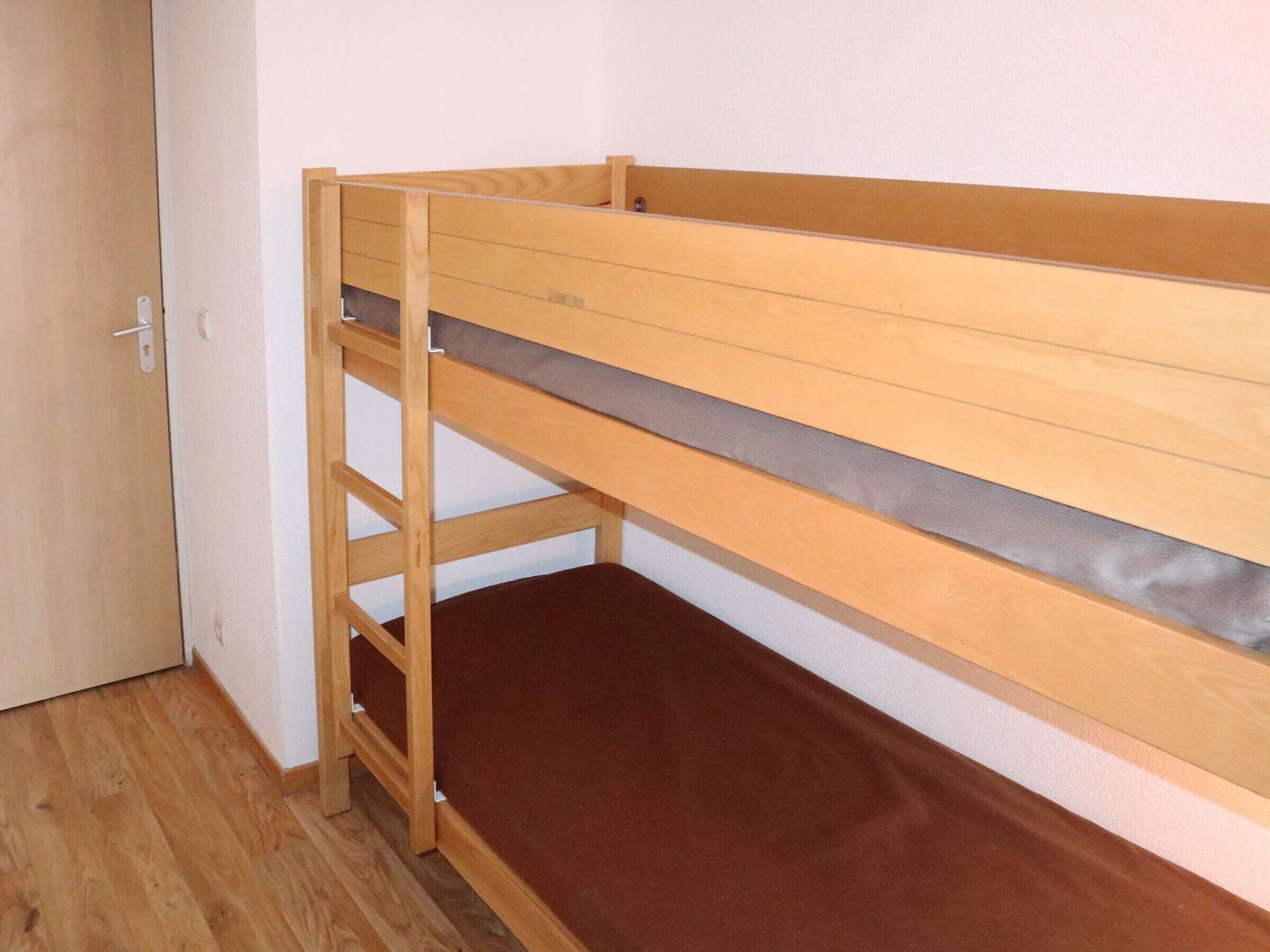 Una cama litera con estructura de madera y colchón marrón.