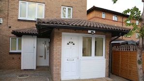 A two-story residential building with a tiled roof, a front door, and a small porch area. - Budget Ensuite Room in Thamesmead (London)