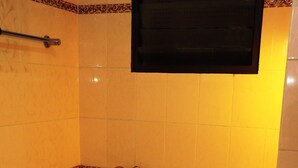 A small bathroom with a toilet, a sink, and a shower. - Hotel Venus (Ootacamund)