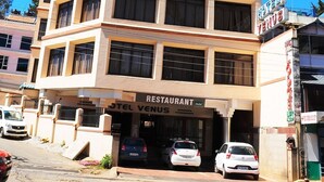 A multi-story hotel with a sign indicating it has a restaurant. - Hotel Venus (Ootacamund)