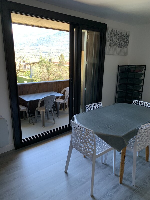 A dining area with a table and chairs, a sliding glass door leading to an outdoor patio, and a wall-mounted storage unit.