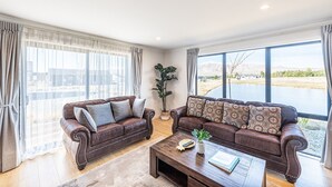 Ein Wohnzimmer mit zwei braunen Ledersofas, einem Couchtisch und großen Fenstern mit Vorhängen.