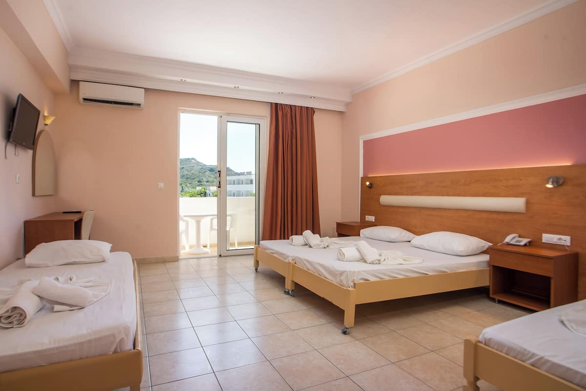 A hotel room with two beds, a TV, a desk, and a sliding glass door to the outside.
