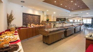 A buffet area with various food items, a wooden counter, and a ceiling with recessed lighting. - Diagoras Hotel (Rhodes)