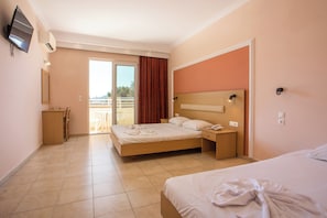 Quarto de hotel com duas camas, televisão, escrivaninha e varanda com vista.