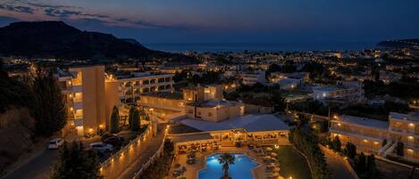 Un resort con piscina, varias construcciones y vista al mar.