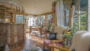 A cozy room with a wooden dining table, chairs, and a bar area with shelves and bottles.