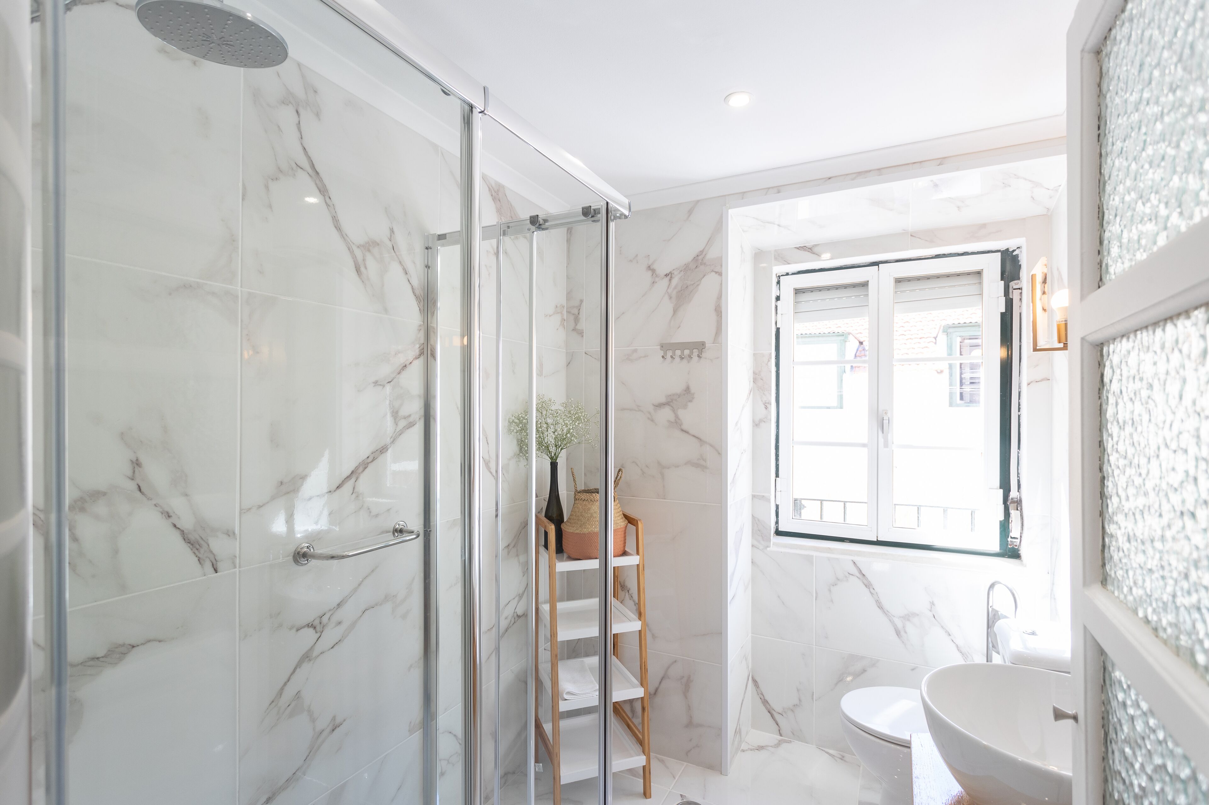 A modern bathroom with a glass shower enclosure, a white sink, and a toilet.