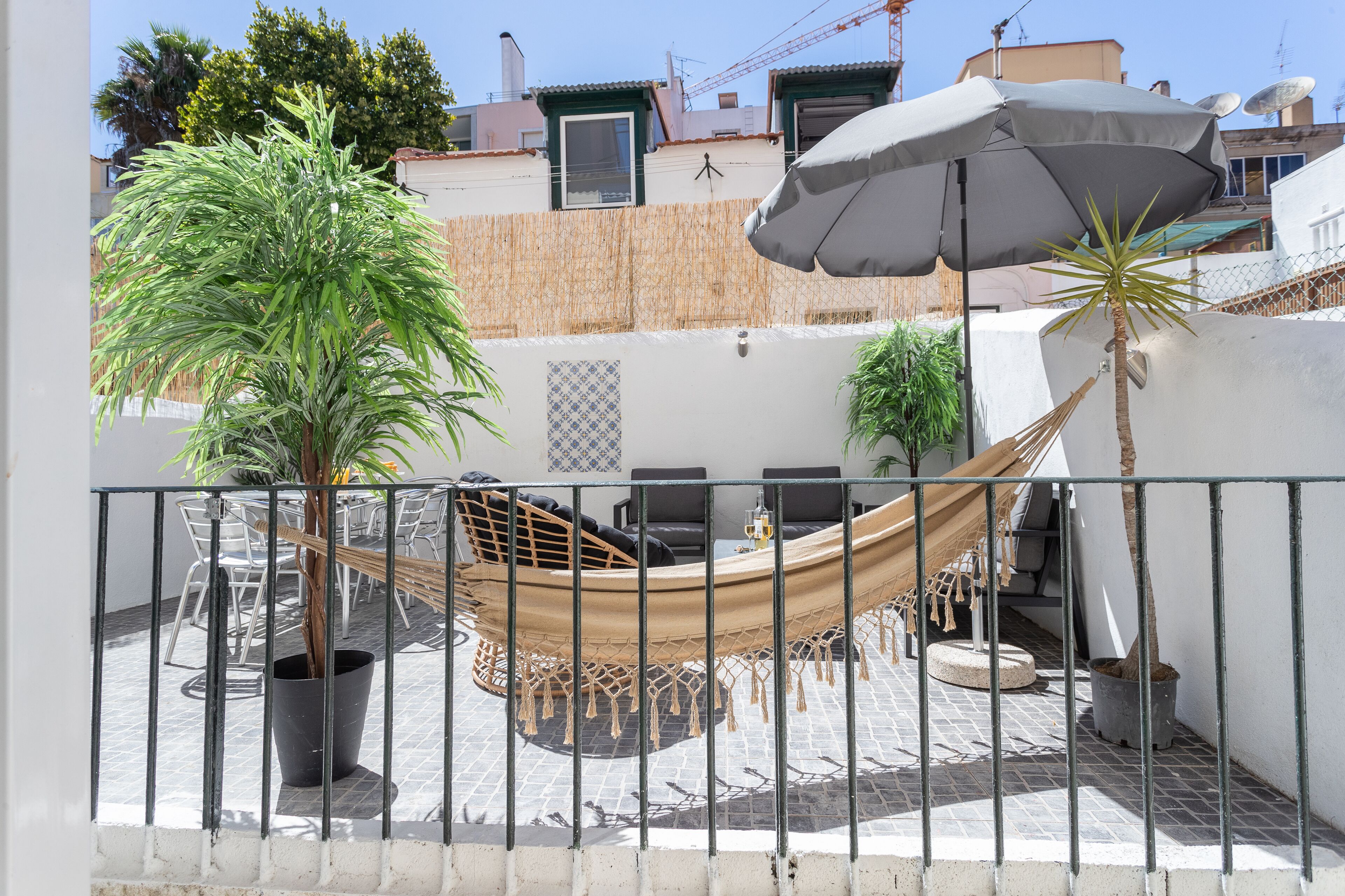 A hammock chair, a potted palm tree, and a patio table with chairs.
