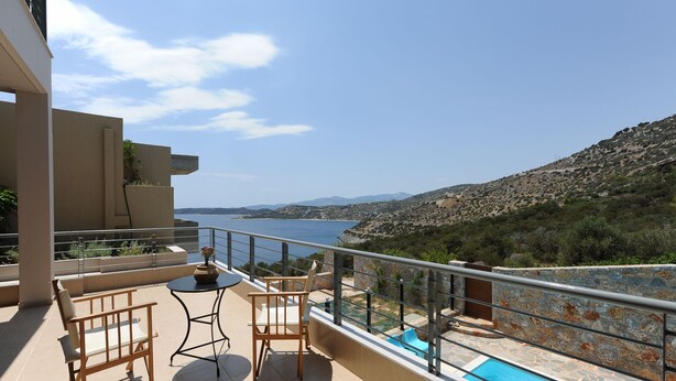 Ein Balkon mit Pool, Gartenmöbeln und Blick auf Meer und Hügel.