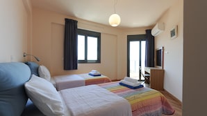 Ein Hotelzimmer mit zwei Betten, einem Schreibtisch, einem Stuhl, einem Fernseher und einem Fenster mit Vorhängen.