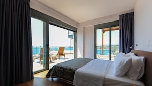 Ein Schlafzimmer mit einem großen Bett, einem Balkon mit Meerblick und einem Sessel.