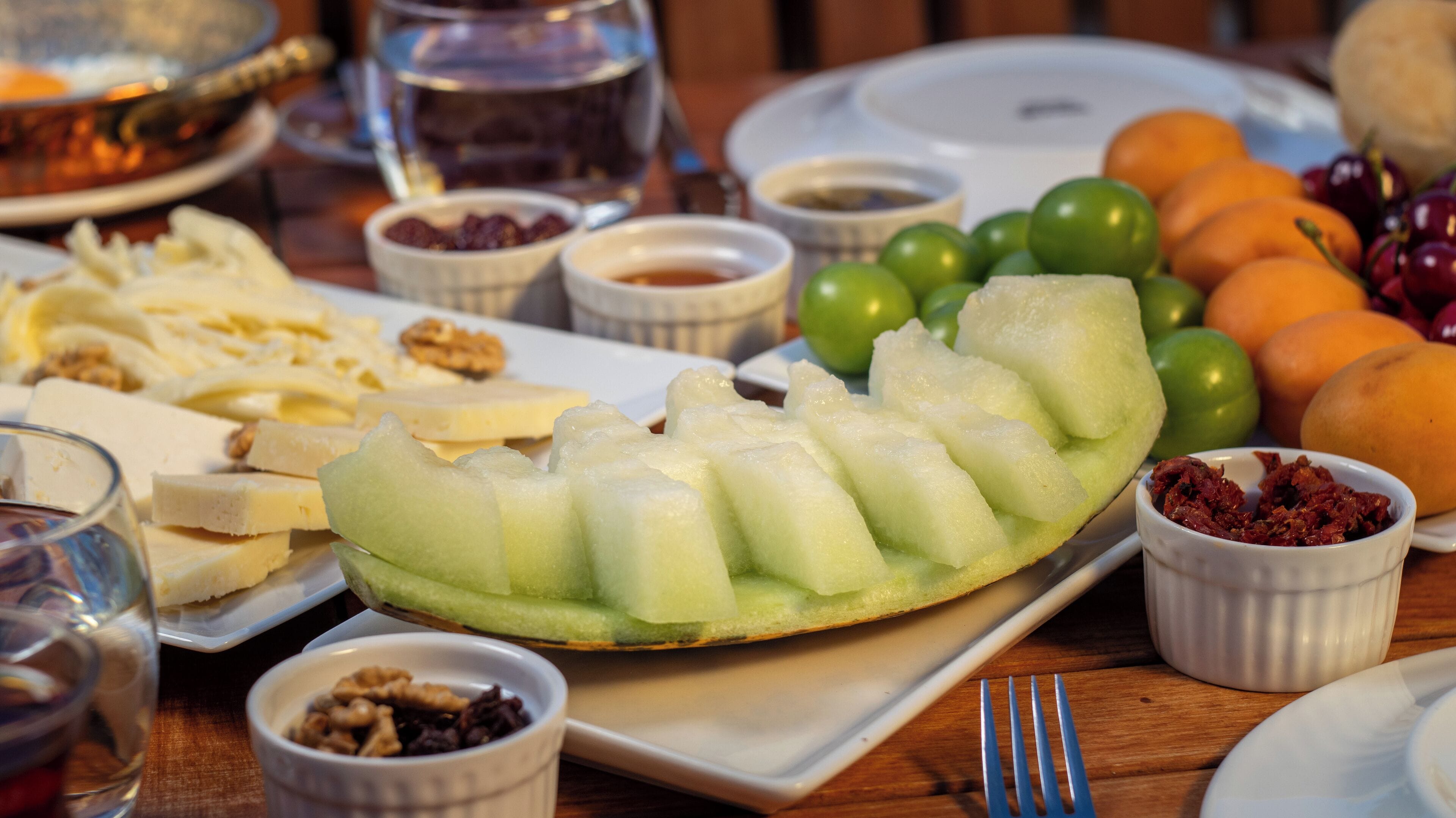 Une table garnie de divers aliments, notamment du fromage, des fruits et des noix.