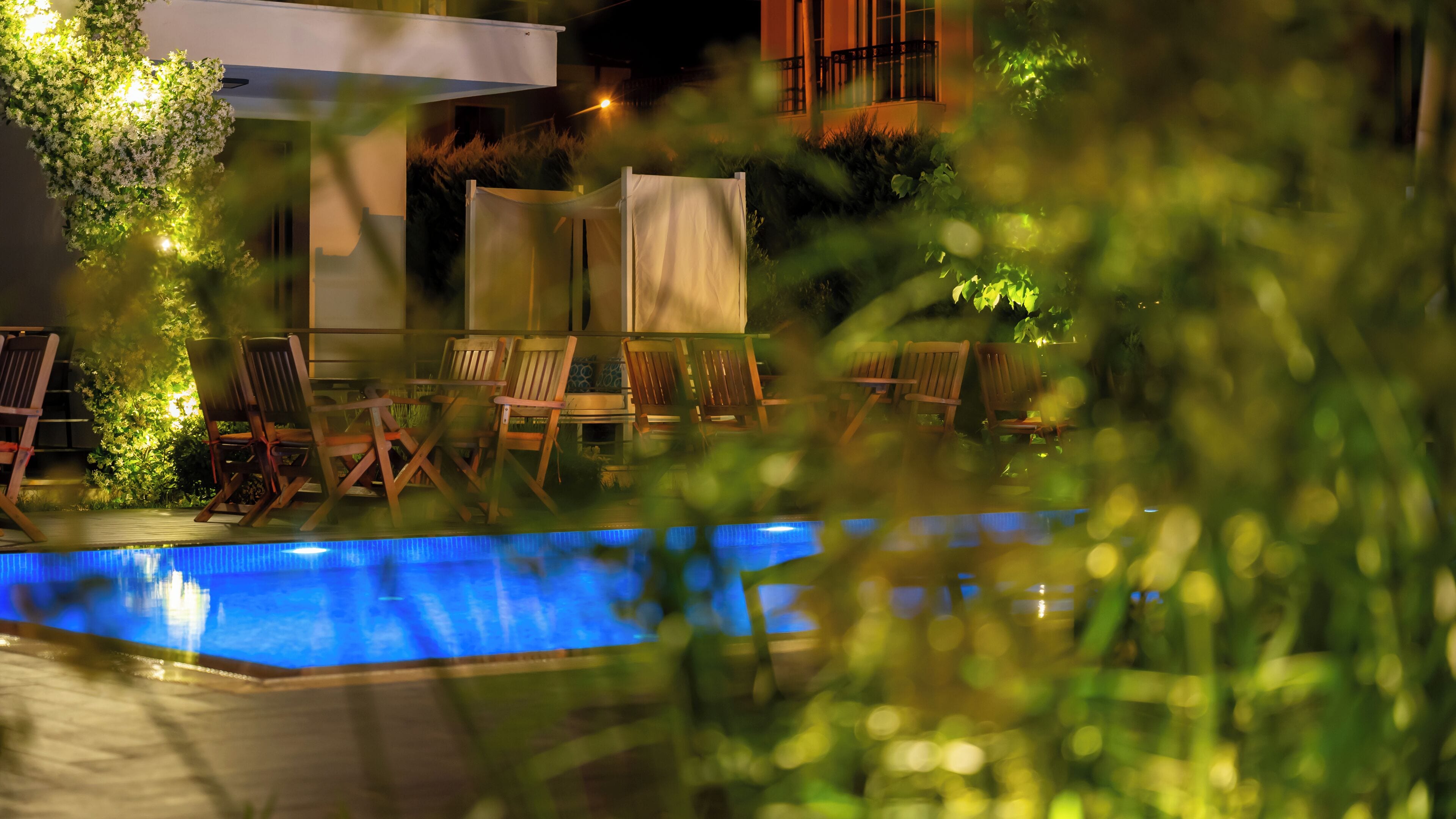 An outdoor pool area with lounge chairs and a covered seating area.