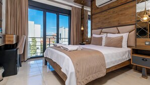 A modern hotel room with a large bed, wooden headboard, and a view of the city through floor-to-ceiling windows. - Cunda Garden  (Ayvalik)