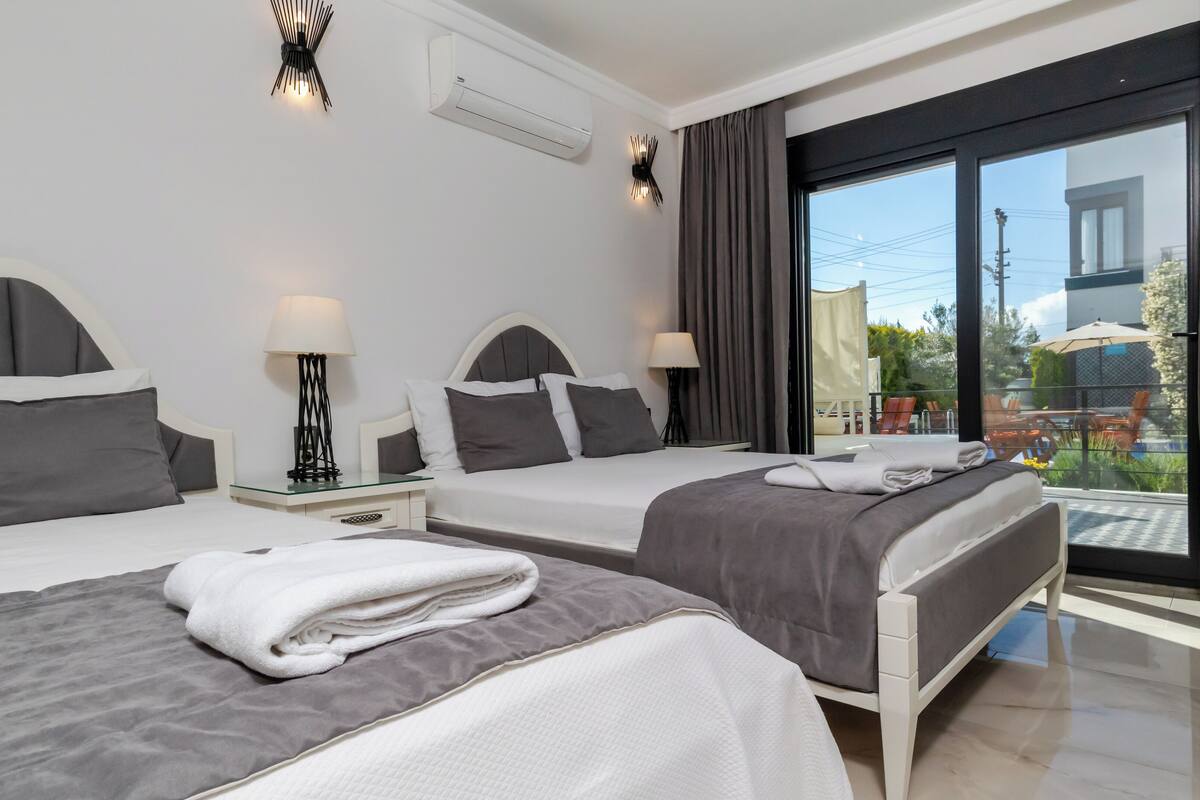 Ein Hotelzimmer mit zwei Betten, einem Balkon und Gartenmöbeln, sowie einem modernen Design.