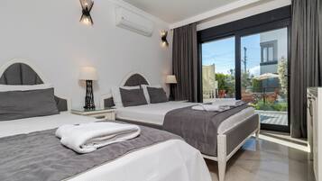 A hotel room with two beds, a balcony with outdoor furniture, and a modern design.