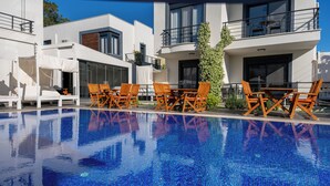 A modern pool area with wooden chairs and a clear blue pool.