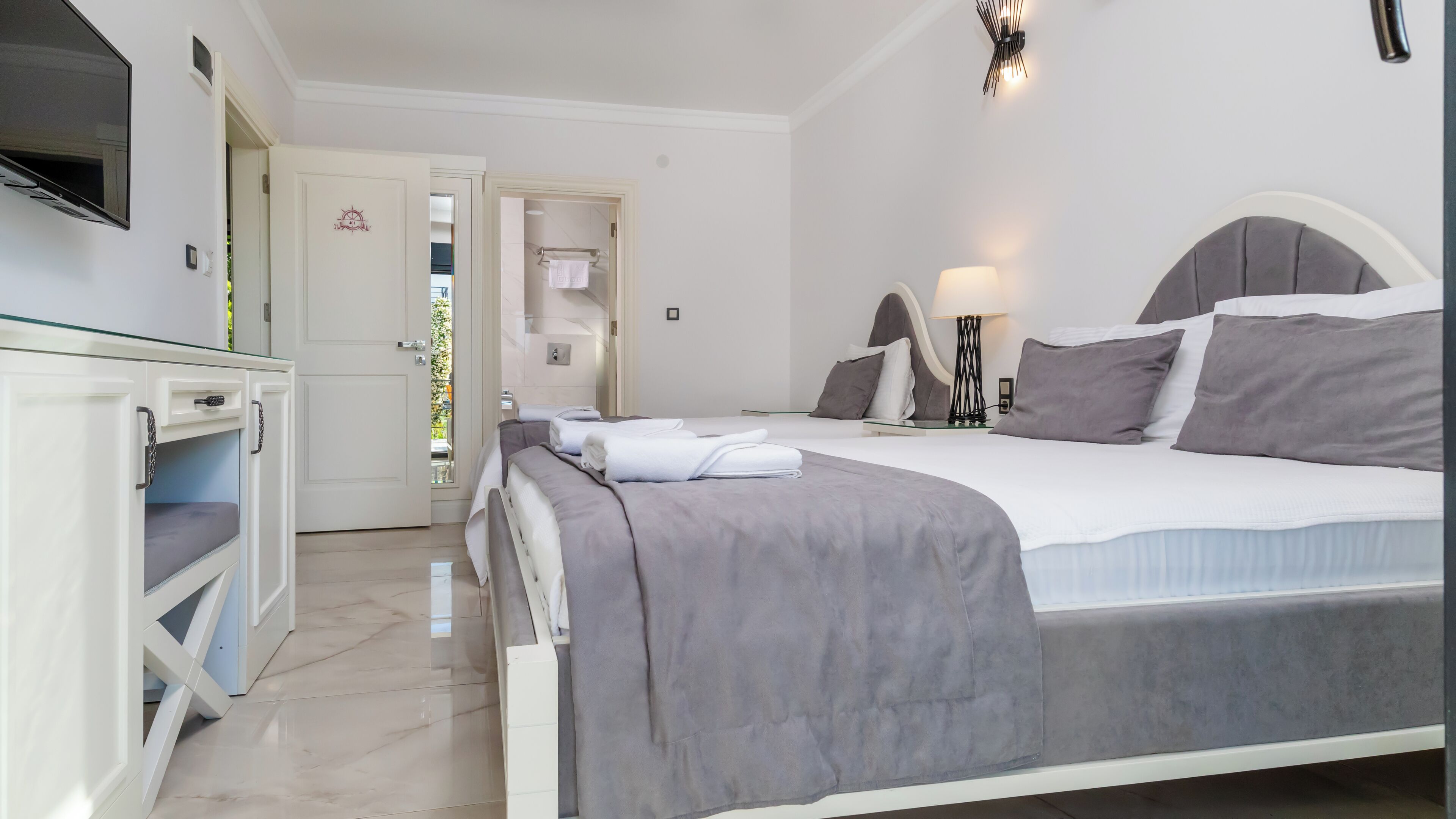 A bedroom with a bed, bedside table, lamp, and a TV mounted on the wall.