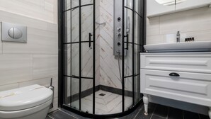 A modern bathroom with a glass-enclosed shower, a white toilet, and a white vanity with drawers. - Cunda Garden  (Ayvalik)